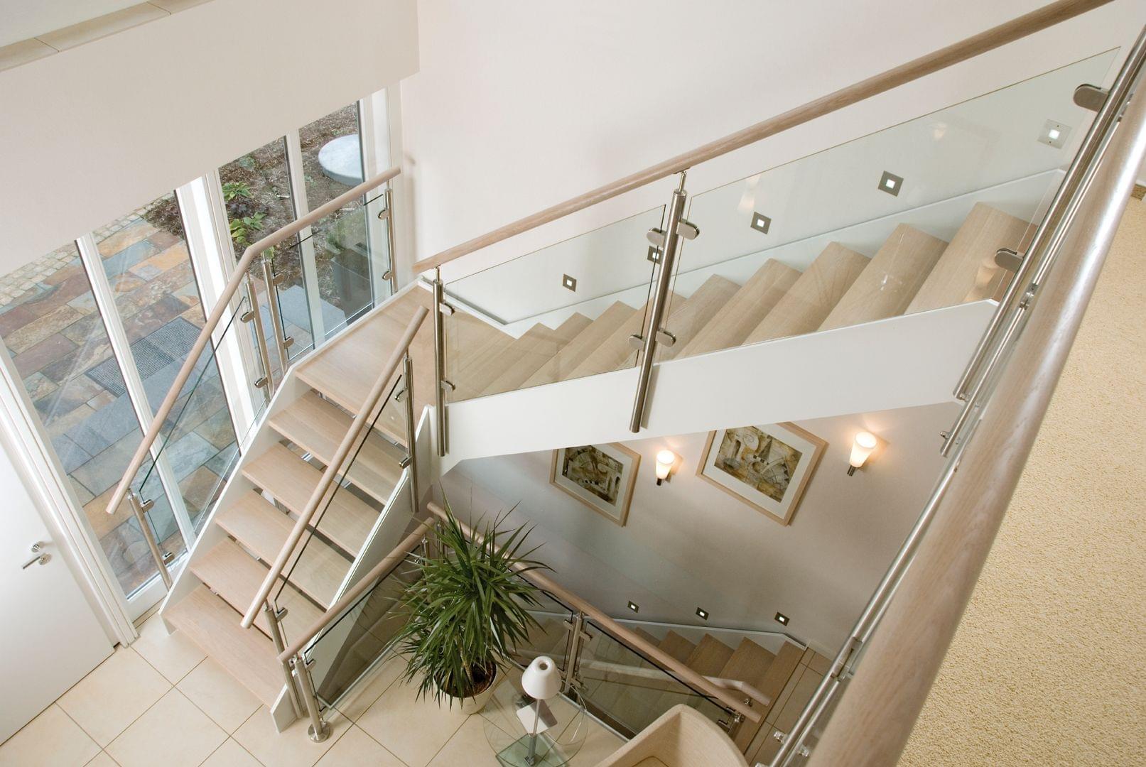 Escalier deux-quart-tournant avec palier marches en bois, limons métalliques laqués blanc rampe en verre | Treppenmeister